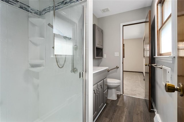 full bath featuring visible vents, toilet, wood finished floors, vanity, and a shower stall