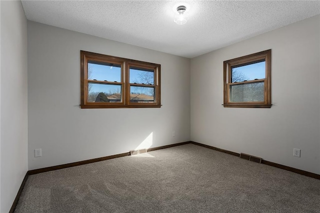 spare room featuring plenty of natural light, visible vents, and baseboards