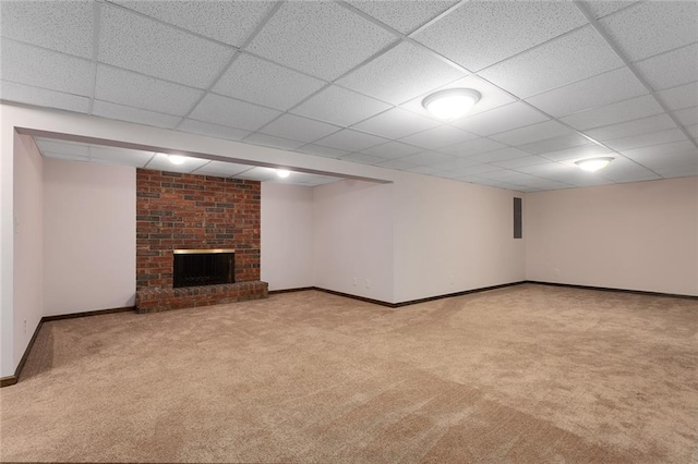 finished below grade area with carpet floors, a brick fireplace, baseboards, and a paneled ceiling