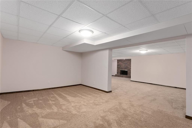 finished below grade area with a paneled ceiling, carpet flooring, a fireplace, and baseboards