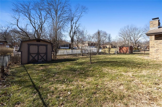 view of yard featuring a storage unit, an outdoor structure, and fence