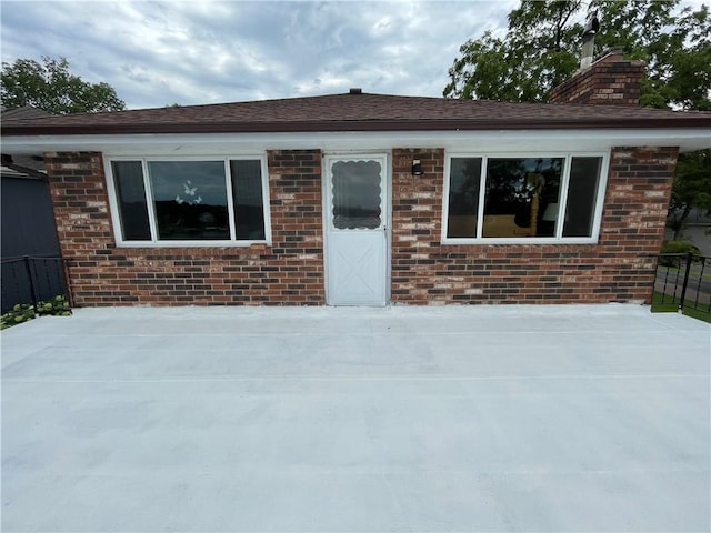 view of front of property featuring brick siding, fence, and a chimney