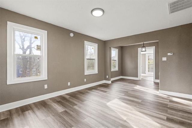 empty room featuring baseboards, visible vents, and wood finished floors