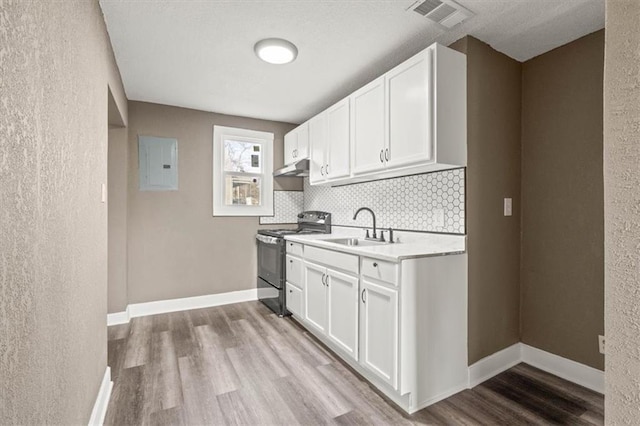 kitchen featuring black range with electric cooktop, white cabinetry, light countertops, and a sink