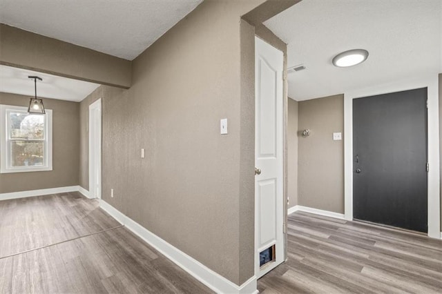 corridor with wood finished floors, visible vents, and baseboards