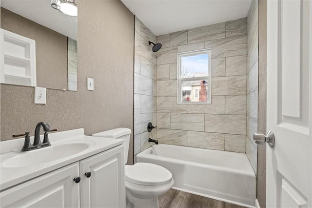 full bath with a textured wall, toilet, shower / tub combination, wood finished floors, and vanity