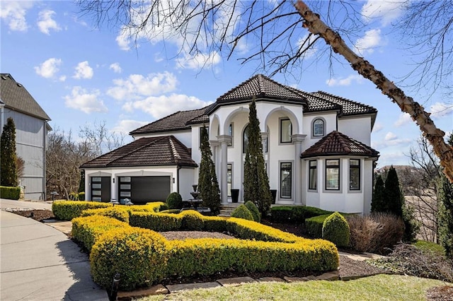 mediterranean / spanish-style house featuring a tile roof, a garage, and stucco siding