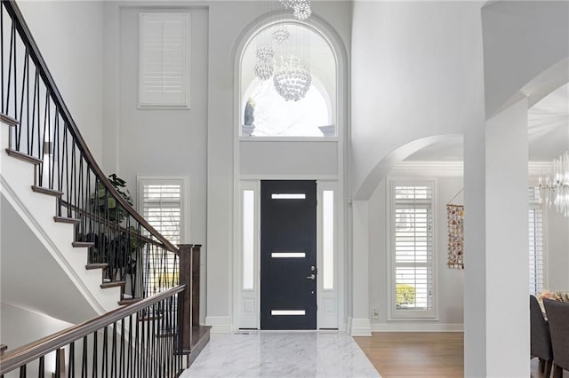 foyer with an inviting chandelier, stairway, arched walkways, and a towering ceiling