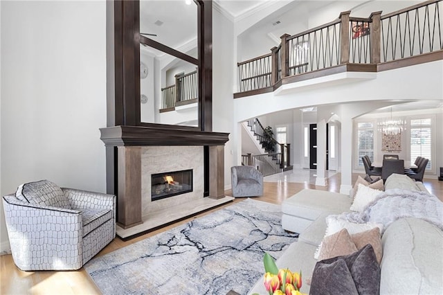 living area with a notable chandelier, wood finished floors, stairway, arched walkways, and a fireplace