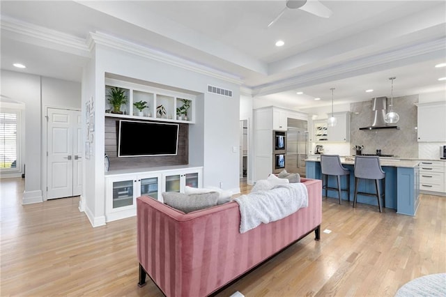 living room with light wood-type flooring, visible vents, recessed lighting, crown molding, and ceiling fan