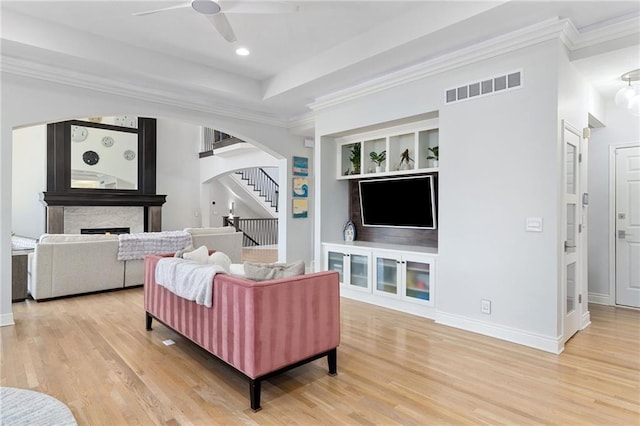 living room featuring visible vents, stairway, light wood-style floors, and a ceiling fan