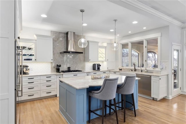 kitchen featuring plenty of natural light, white cabinetry, gas stovetop, light wood-style floors, and wall chimney exhaust hood