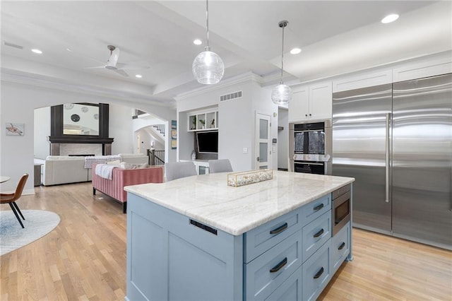 kitchen with a kitchen island, light wood-style flooring, recessed lighting, arched walkways, and built in appliances