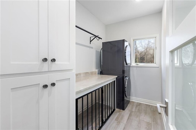 bathroom featuring stacked washer and clothes dryer and baseboards