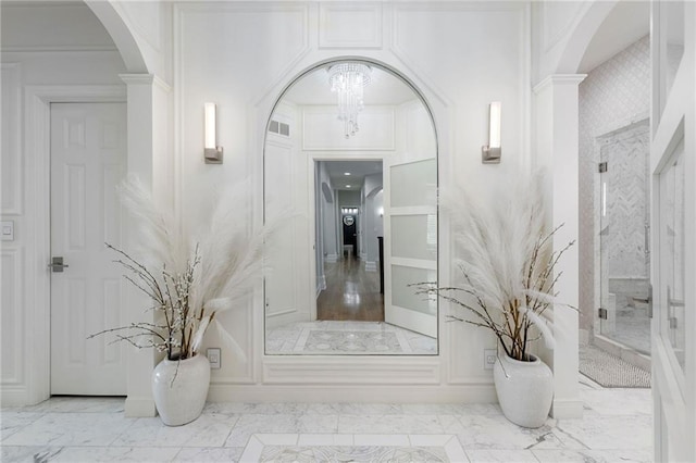 bathroom featuring an inviting chandelier, visible vents, marble finish floor, and a walk in shower