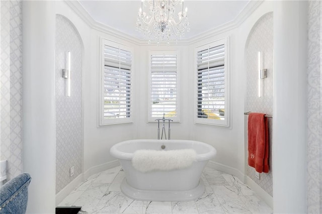 full bath featuring baseboards, ornamental molding, an inviting chandelier, a freestanding tub, and marble finish floor