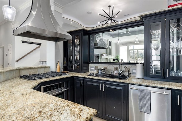 kitchen with dark cabinets, a sink, extractor fan, appliances with stainless steel finishes, and tasteful backsplash