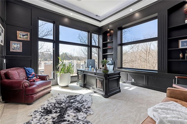 carpeted home office with a decorative wall, built in shelves, and a healthy amount of sunlight