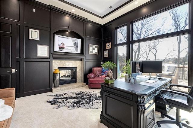 office area with visible vents, ornamental molding, carpet, a decorative wall, and a premium fireplace