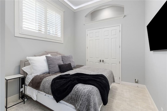 carpeted bedroom featuring a closet, baseboards, and crown molding