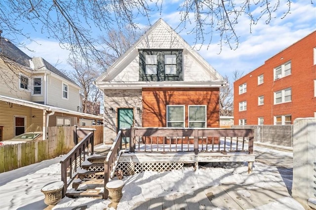 snow covered property featuring a deck and fence