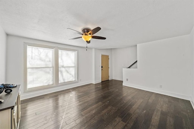 unfurnished living room featuring a textured ceiling, ceiling fan, dark wood finished floors, and baseboards