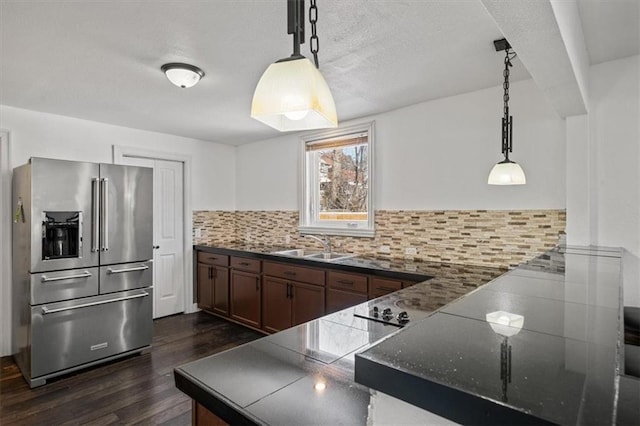 kitchen with a sink, hanging light fixtures, backsplash, and high end refrigerator