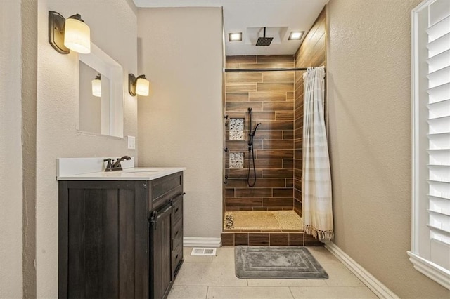 bathroom featuring visible vents, a stall shower, vanity, and baseboards