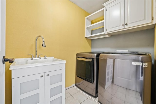 washroom with light tile patterned floors, a sink, cabinet space, and washer and dryer