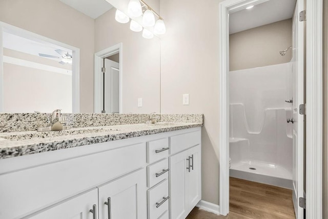 bathroom featuring hardwood / wood-style flooring, ceiling fan, vanity, and walk in shower