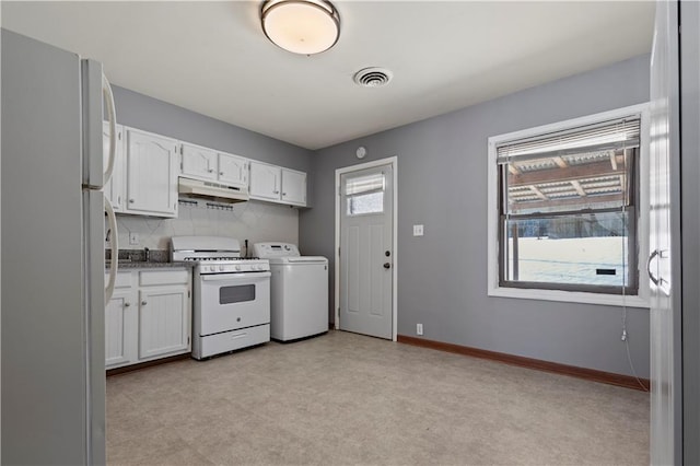 kitchen featuring white appliances, under cabinet range hood, washer / clothes dryer, and white cabinets