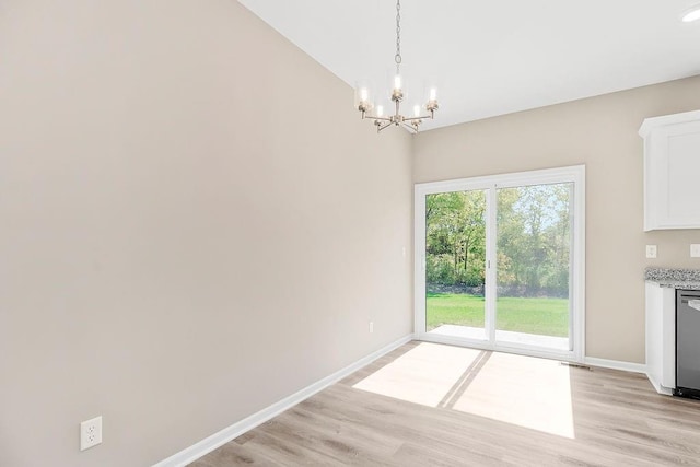 unfurnished dining area featuring an inviting chandelier and light hardwood / wood-style floors