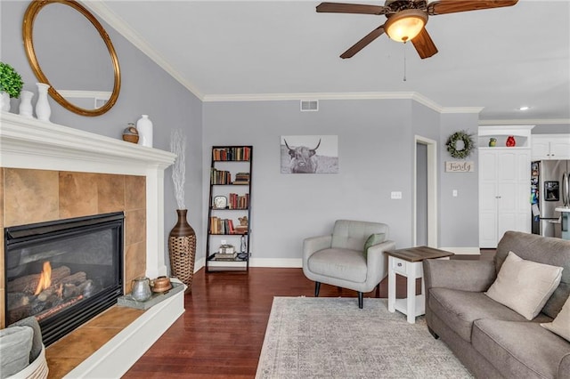 living area with a tile fireplace, visible vents, crown molding, and wood finished floors