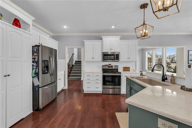 kitchen with stainless steel appliances, white cabinetry, a sink, and decorative light fixtures