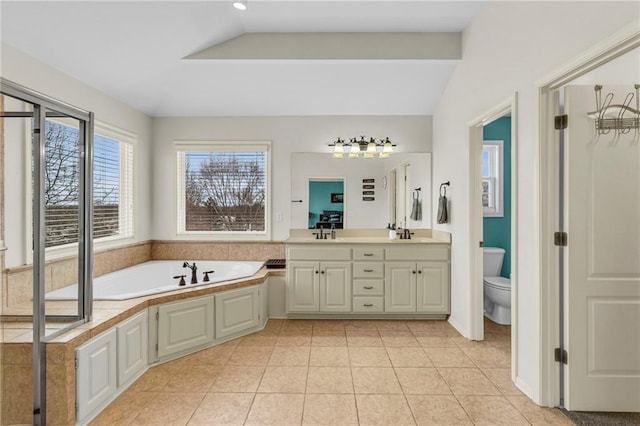 bathroom featuring tile patterned flooring, a garden tub, toilet, a sink, and double vanity