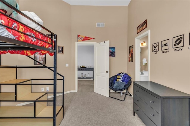 carpeted bedroom with a high ceiling, connected bathroom, and visible vents