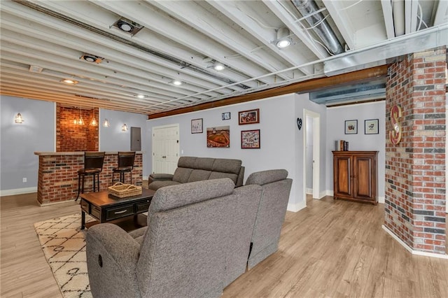 living room featuring light wood-type flooring, baseboards, and a dry bar