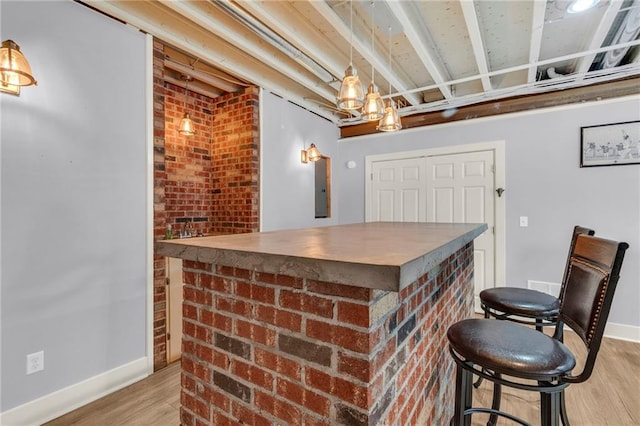 bar with baseboards, a bar, and light wood-style floors