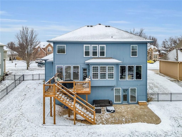 snow covered back of property featuring a patio area, a fenced backyard, stairs, and a wooden deck