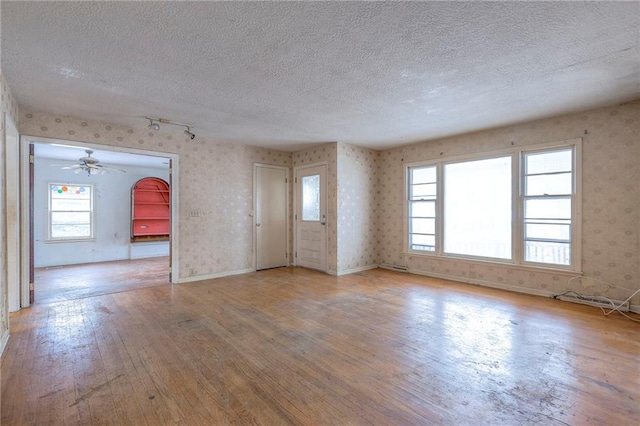 unfurnished living room featuring light hardwood / wood-style flooring and a textured ceiling