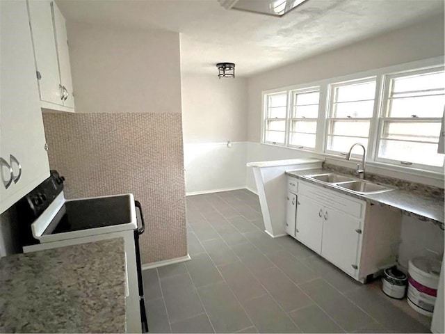 kitchen with sink, electric range, and white cabinets