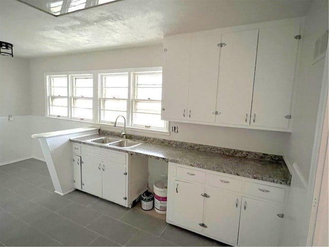 kitchen with light tile patterned floors, sink, and white cabinetry