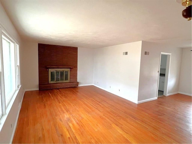 unfurnished living room with a brick fireplace and wood-type flooring