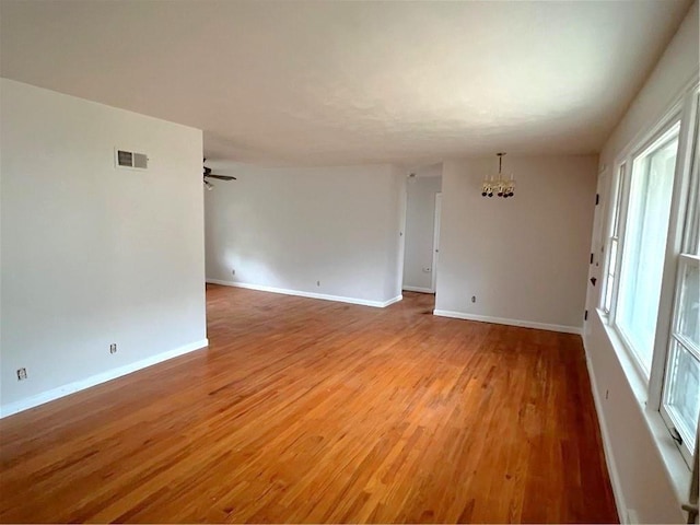 unfurnished room featuring light hardwood / wood-style floors and ceiling fan with notable chandelier