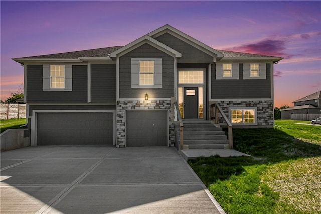 12414 Adam St, Excelsior Springs, MO 64024 - bi-level home with stone siding, a garage, driveway, and a lawn
