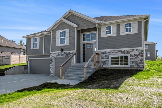 12414 Adam St, Excelsior Springs, MO 64024 - bi-level home with stone siding, an attached garage, and driveway