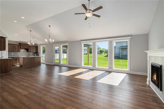 12414 Adam St, Excelsior Springs, MO 64024 - unfurnished living room featuring high vaulted ceiling, a lit fireplace, baseboards, ceiling fan, and dark wood-style flooring