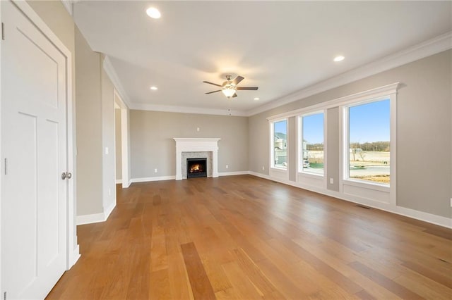 unfurnished living room featuring hardwood / wood-style flooring, ornamental molding, and ceiling fan