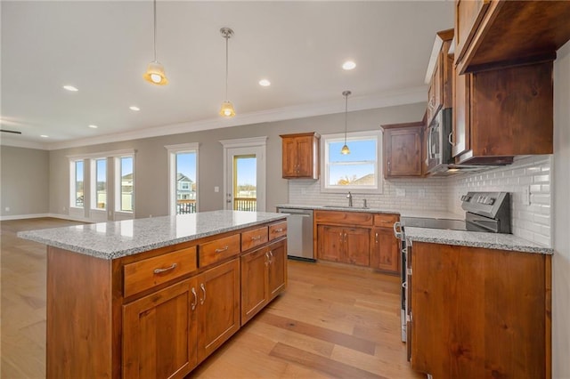 kitchen featuring light hardwood / wood-style flooring, stainless steel appliances, light stone counters, decorative light fixtures, and a kitchen island