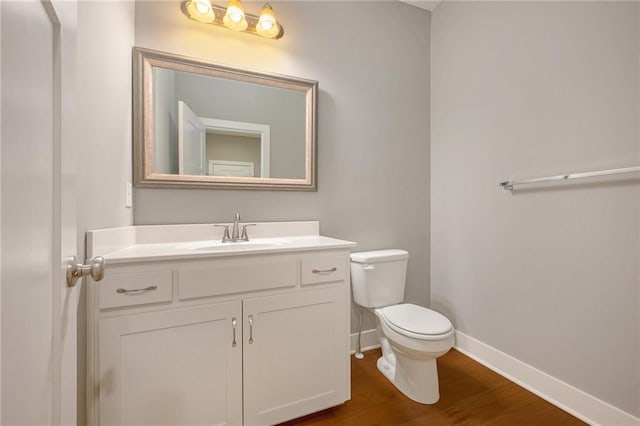 bathroom with toilet, vanity, and hardwood / wood-style floors